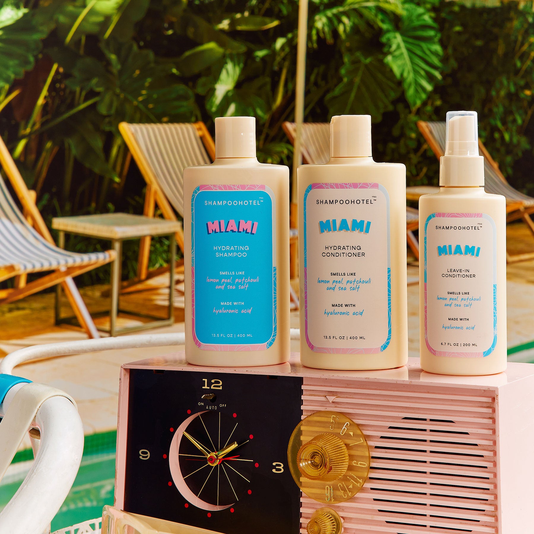 Three bottles of Shampoo Hotel Miami products on a vintage radio with a tropical setting.